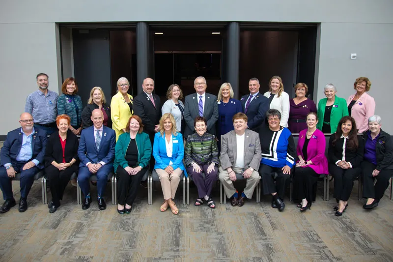 Group photo of past presidents and leaders posing together in a conference setting, dressed in formal and business attire, with a modern indoor backdrop.