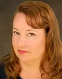 A professional headshot of a woman with long, light brown hair styled softly to one side. She has a neutral expression and is wearing a dark top.