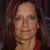 A headshot of a woman with shoulder-length straight hair, wearing a dark red top. She has a calm expression and is photographed against a softly lit indoor background.